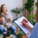 crop psychologist taking notes during appointment