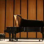 a black piano sitting in front of a wooden wall