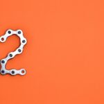 Metal chain forming the number 2 on a bright orange background, perfect for design projects.