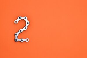 Metal chain forming the number 2 on a bright orange background, perfect for design projects.